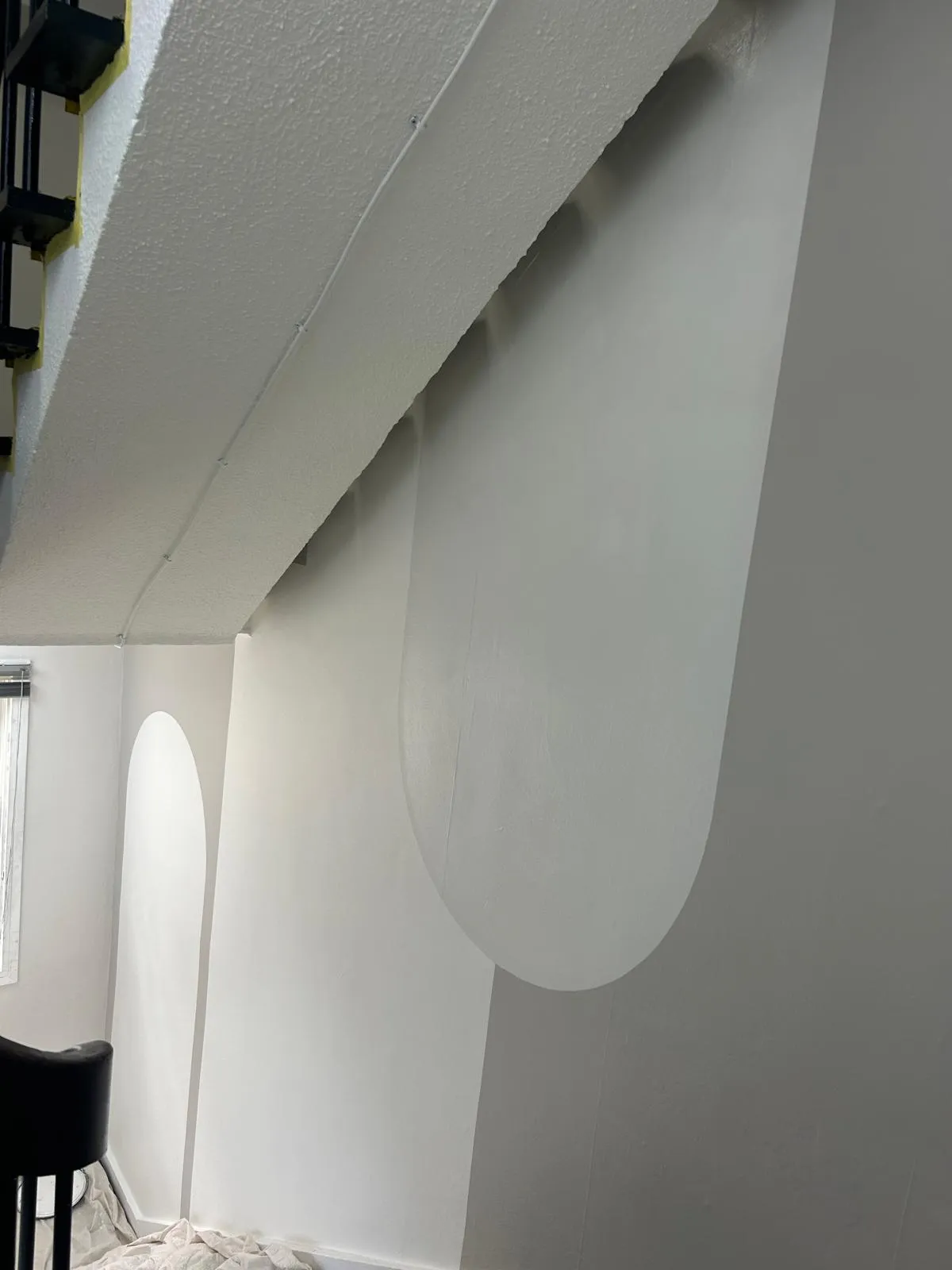 Tall geometric grey feature wall being painted beside a stairwell
