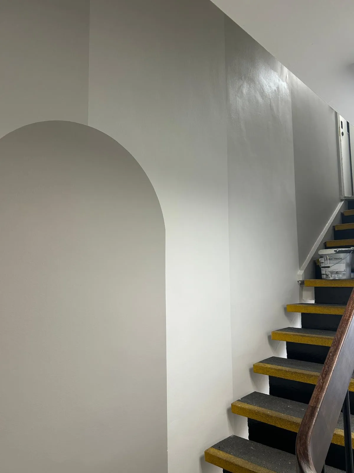 A stairwell in progress with a geometric grey and white painted design beside dark steps